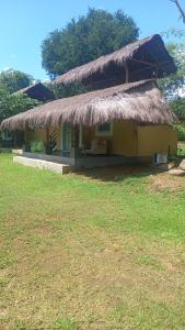 una pequeña cabaña con techo de paja en un campo en Web of Life Resort Wasgamuwa, en Talakolawela