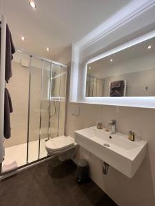 ein Badezimmer mit einem Waschbecken, einem WC und einem Spiegel in der Unterkunft Hotel Paula Norderney in Norderney