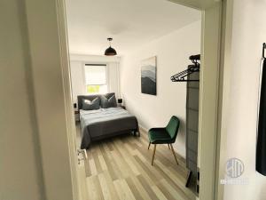 a bedroom with a bed and a green chair at KMHosting Luxe Apartment Chemnitz-Zentrum in Chemnitz