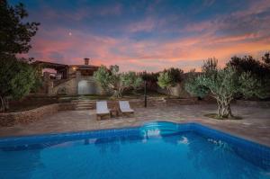 een zwembad met twee stoelen en een huis bij Villa Viva Brac - Pool - Meerblick in Povlja