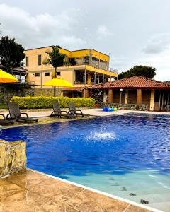 basen z leżakami i parasolami obok budynku w obiekcie Hotel Campestre Los Mangos w mieście Quimbaya