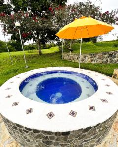 parasol obok małego okrągłego basenu w obiekcie Hotel Campestre Los Mangos w mieście Quimbaya