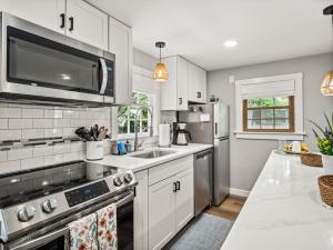 a kitchen with white cabinets and a stainless steel refrigerator at Cape Cod Cottage, near Beach, Hot Tub, AC, Dog Friendly in Yarmouth