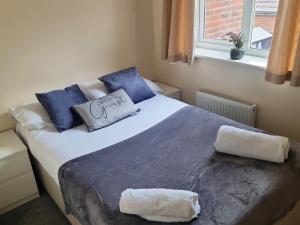 Un dormitorio con una cama grande con almohadas azules y una ventana en Room for a few at H-Cue, en Kent