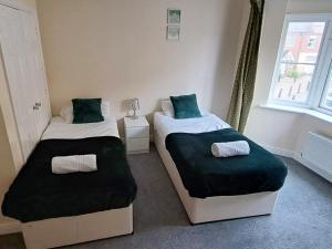 two beds in a small room with green pillows at Room for a few at H-Cue in Kent