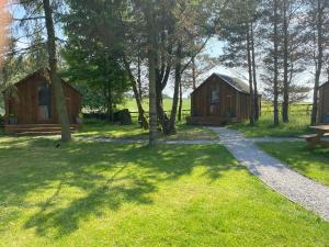 two cottages in a park with a bench and trees at Cow Close Camping Pods in Leyburn
