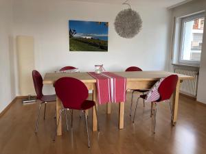 una mesa de comedor con sillas rojas alrededor en Ferienwohnung Fernsicht, en Markdorf