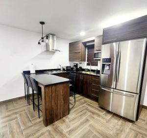 a kitchen with a stainless steel refrigerator and wooden cabinets at Departamento Pitagoras No 2 in Ciudad Juárez