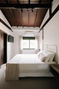 a bedroom with a large white bed with a window at Pousada Zama in Camburi