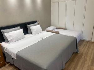 Duas camas num quarto com lençóis e almofadas brancos em Suíte no Jardim Guedala em São Paulo