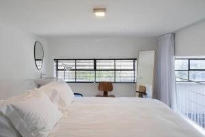 a bedroom with a large white bed and two windows at A Bauhaus Gem - Prime Location in Tel Aviv