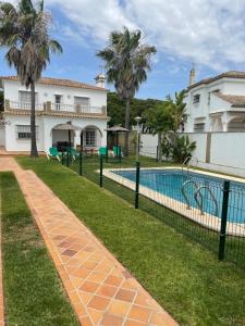 una piscina frente a una casa con palmeras en LA BARROSA VILLA, en Chiclana de la Frontera