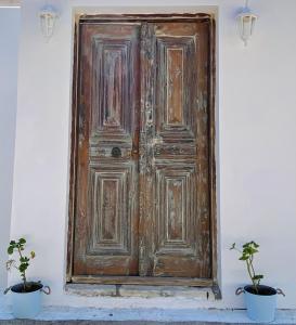 an old wooden door with two potted plants in front of it at To Petrino in Meyisti