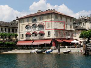 un gran edificio con barcos en el agua de enfrente en -Ortaflats- Appartamento L'Angolo, en Orta San Giulio