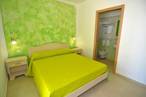 a bedroom with a yellow bed and a bathroom at B&B Lu Cantoru in Marina di Pescoluse