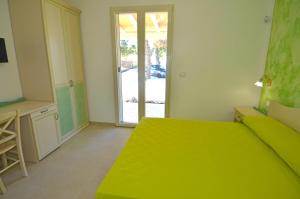 a bedroom with a green bed and a sliding glass door at B&B Lu Cantoru in Marina di Pescoluse