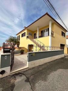 uma casa amarela com uma varanda numa rua em Adraga Beach&Village House em Colares