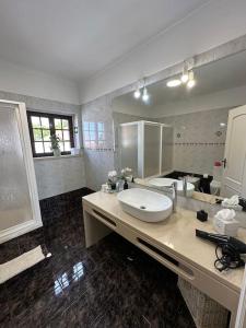 uma casa de banho com um lavatório e um espelho grande em Adraga Beach&Village House em Colares