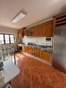 uma cozinha com armários de madeira e um frigorífico de aço inoxidável em Adraga Beach&Village House em Colares