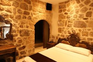 um quarto com uma cama e uma parede de pedra em Mardin Bey Konağı Hotel em Mardin