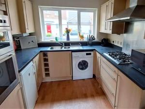 a kitchen with a sink and a washing machine at Room for a few at H-Cue in Kent