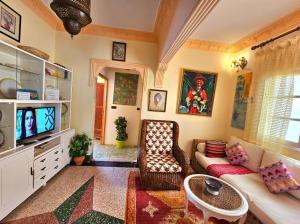 ein Wohnzimmer mit einem Sofa und einem TV in der Unterkunft Dar Khadija in Asilah