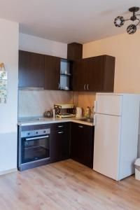 uma cozinha com armários castanhos e um frigorífico branco em Апартамент Езерото em Triavna