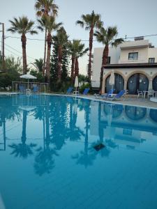 una gran piscina con palmeras en el fondo en Dolphin Apartments, en Faliraki