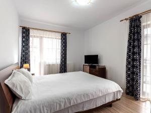 a bedroom with a white bed with curtains and a television at Apartamente Simona Brasov in Braşov