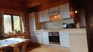 MooswaldKärnten Landhof in Alleinlage Nähe Millstättersee Ferienwohnung im ersten Stock的厨房配有白色橱柜、桌子和窗户