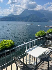 a table and chairs on a deck with a view of the water at Divina Vita Apartments in Varenna