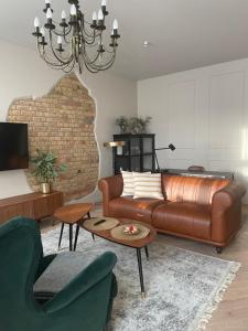 a living room with a brown leather couch and a table at Lindens apartments in the heart of the city in Panevėžys