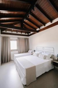 1 dormitorio con 2 camas blancas y techo de madera en Pousada Zama en Camburi