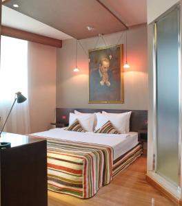 a bedroom with a bed with a painting on the wall at Design Hotel Mr President in Belgrade