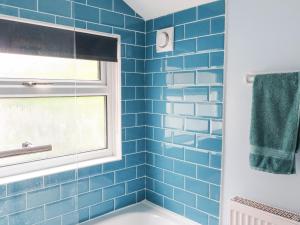 een blauw betegelde badkamer met een raam en een bad bij Seaside Retreat in Lowestoft