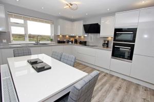 a kitchen with white cabinets and a white table and chairs at Sea Breeze in Clachan
