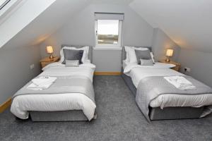 a attic room with two beds and a window at Sea Breeze in Clachan