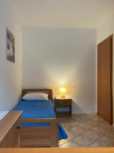 ein Schlafzimmer mit einem Bett und einem Nachttisch mit einer Lampe in der Unterkunft Appartamenti Allegrini Tuenno in Tuenno