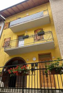 um edifício amarelo com duas varandas e flores nele em Appartamenti Allegrini Tuenno em Tuenno