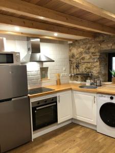 a kitchen with white cabinets and a stove top oven at Apartamentos El Arroyo in Armal