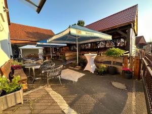 un patio con mesas, sillas y una sombrilla en 1852 Landgasthof- Ferienwohnung, en Elze