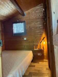 - une chambre dans une cabane en rondins avec un lit et une fenêtre dans l'établissement les petits chalets de DUDU, à La Voulte-sur-Rhône