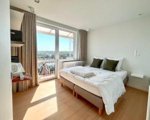 a bedroom with a bed with a large window at Viviane - Beautifull view, Garage, 200m from beach in De Panne