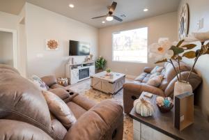 a living room with brown leather couches and a tv at New South Zion Coral Cliffs - 4 bed, 3 bath, hot tub, deck in Hildale