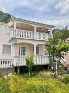 a large pink house with a white balcony at Village house Iva in Virpazar