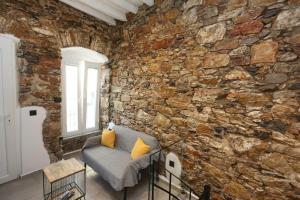 a room with a stone wall with a couch and a window at Stones By Syros Bnb in Ermoupoli