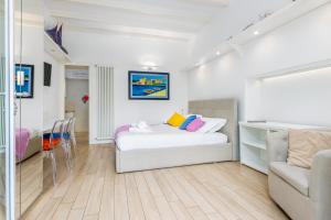 a white bedroom with a bed and a couch at FEEL - Patio del Sole in Bergamo