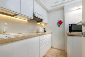 a kitchen with white cabinets and a sink and a microwave at FEEL - Patio del Sole in Bergamo