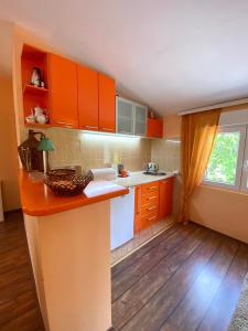 cocina con armarios de color naranja y encimera en Village house Iva, en Virpazar