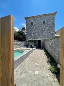 uma vista exterior de um edifício de pedra com uma piscina em Melitsina Village Hotel em Kardamili